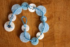 a blue and white beaded bracelet on a wooden table with beads attached to it