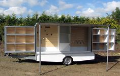 a small white trailer with open shelves on the side