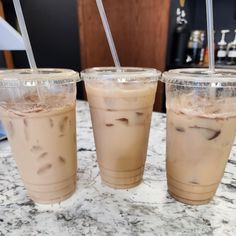 three iced drinks sitting on top of a marble counter