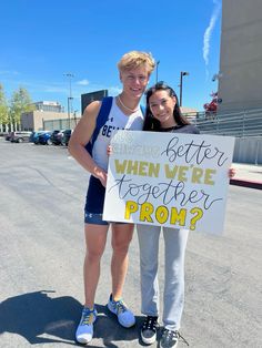 two people standing next to each other holding a sign that says, better when we together prom?