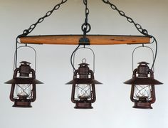 three old fashioned hanging lanterns with chains attached to the light fixture, on a white wall