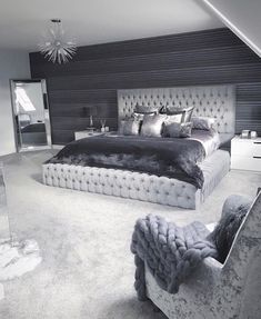 a large bed sitting in the middle of a bedroom next to a chair and dresser