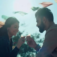 a man and woman holding drinks in their hands while looking at each other's eyes