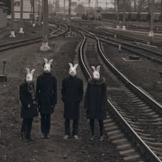 three people with bunny ears on their heads standing in front of train tracks at night