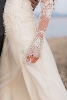 the bride and groom are holding each other's hands on their wedding day at the beach