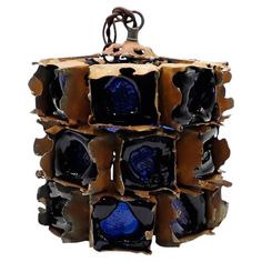 a blue and brown vase with holes in the middle on a white background, hanging from a metal hook