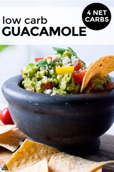 a black bowl filled with guacamole and tortilla chips on top of a wooden table