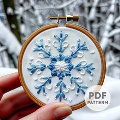 a hand embroidered snowflake is shown in front of a white background with blue accents