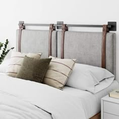 an unmade bed with white linens and wooden headboard, in a bedroom