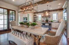 a dining room table with chairs and a bench in front of an open kitchen area