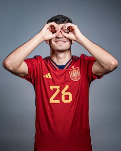 a man in a red shirt is holding his hands to his face and smiling at the camera