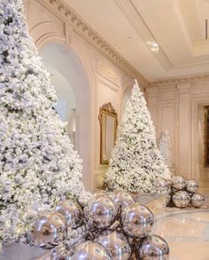 christmas trees and decorations in the lobby of a luxury hotel, decorated with white flowers