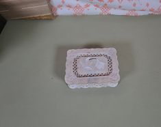 a small glass dish sitting on top of a table next to a bed with pink and white bedspread