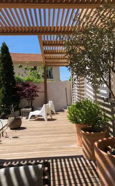 a wooden deck with potted plants on it and an attached pergolated roof