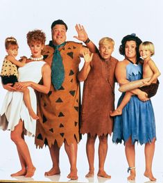 a group of people in costumes standing next to each other on a white background with one person holding a child