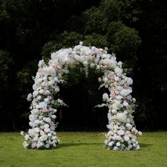 a white and pink floral arch in the grass