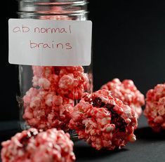 a jar filled with red and white candies next to a sign that says ab normal brain