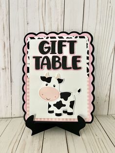 a sign that says gift table with a cow in the center and words on it