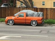 an orange pick up truck with a tarp on it's hood parked in front of a house