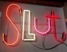 a neon sign that is on the side of a building with wires attached to it