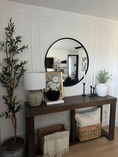 a living room with a large mirror on the wall next to a wooden table and wicker baskets