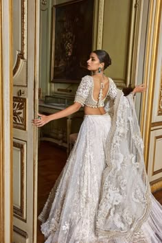 a woman in a white wedding dress standing next to an open door with her hand on her hip