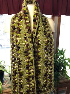 a green and brown crocheted scarf on a mannequin