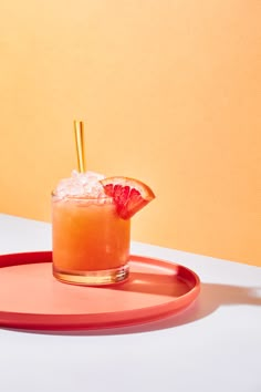 an orange drink on a red tray with strawberries and garnish in it