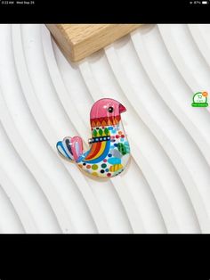 a colorful bird sitting on top of a white table next to a wooden block with a sign