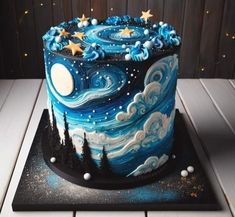 a blue and white cake decorated with stars and the night sky on top of it