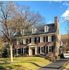 a large brick house sitting on top of a lush green field next to a forest