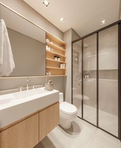 a bathroom with a toilet, sink and shower stall in the background is a walk - in shower