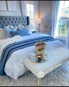 a bedroom with blue and white bedding, flowers on the foot board, and a tray