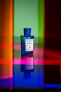 a bottle of perfume sitting on top of a table next to a multicolored wall