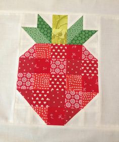 a patchwork strawberry is on top of a white tablecloth with red and green designs