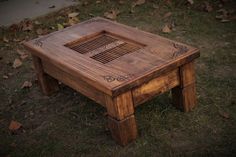 a wooden table sitting on top of grass next to a leaf covered ground with leaves around it