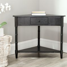 a black table with two drawers and a plant on it next to a white vase