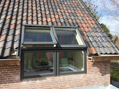 an open window on the side of a brick building with tiled roof and red tiles