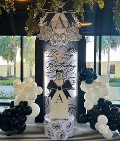 balloons and decorations are on display in front of a window at a party with black and white decor