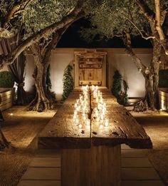 an outdoor dining area with candles lit up on the table and trees in the background