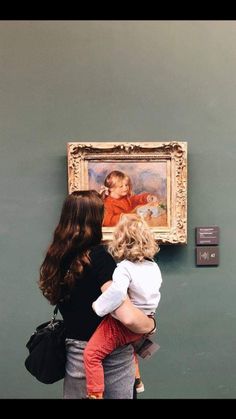 two women and a child looking at a painting