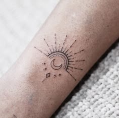 a small sun and moon tattoo on the left arm, with stars in the background