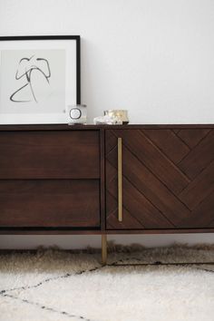 the sideboard is made from wood and has brass hardware on it, along with a white rug