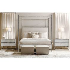 a white bed sitting in a bedroom next to two nightstands and a mirror dresser