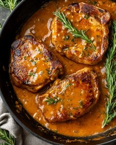 pork chops with gravy in a skillet on top of a table