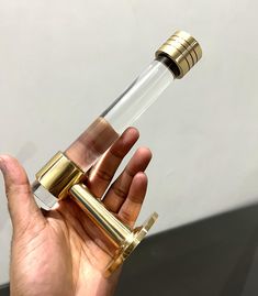 a hand holding a small glass tube with gold trim