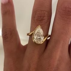 a woman's hand with a ring on it and a pear shaped diamond in the middle