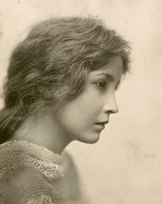 an old black and white photo of a woman with long hair wearing a lacy top