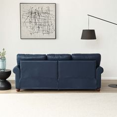 a living room with a blue couch and two black lamps on the wall next to it