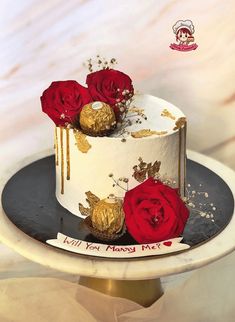 a white and gold cake with red roses on top